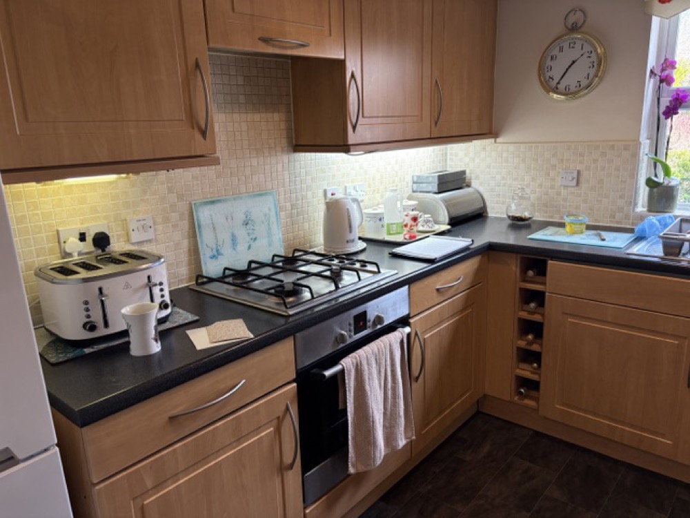 A kitchen in Malvern before the makeover: dark oak doors with a black worktop