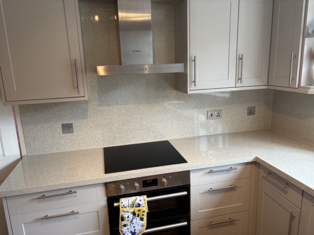 The same kitchen after the makeover: cream shaker doors, light stone worktop and a clean splashback