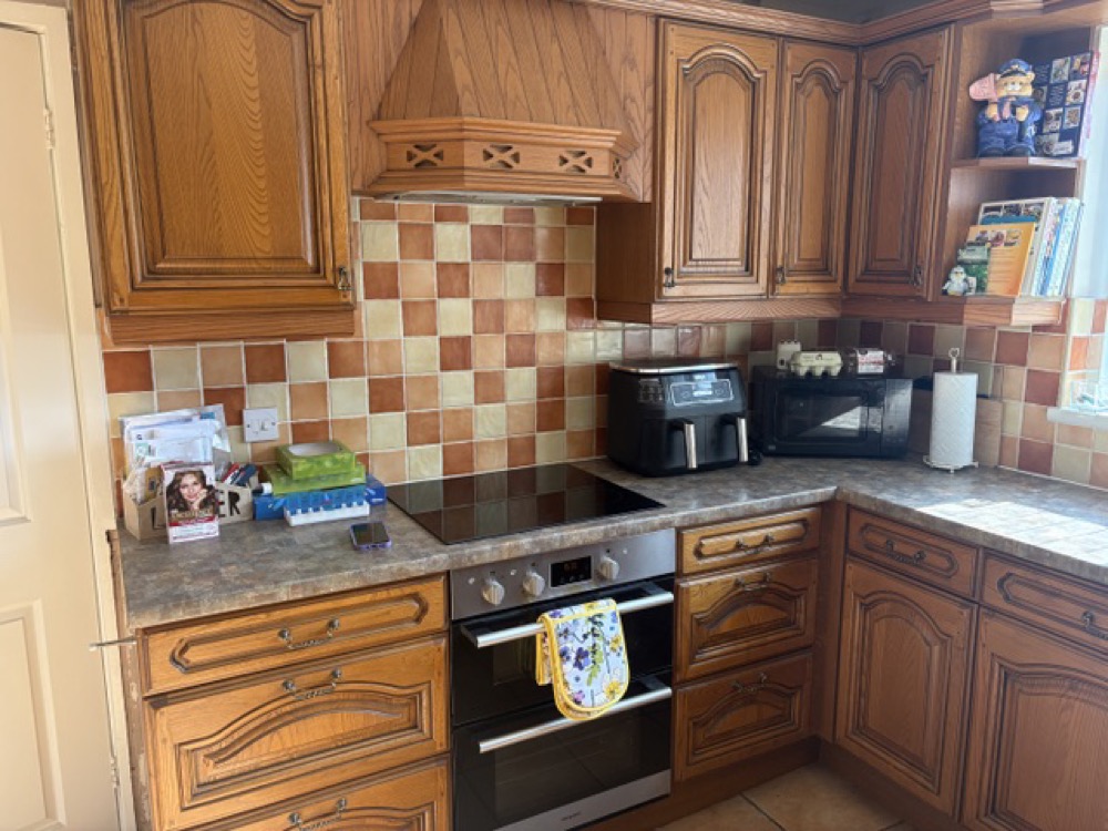 Kitchen before the makeover: dark oak doors with a dated worktop and terracotta tiled splashback